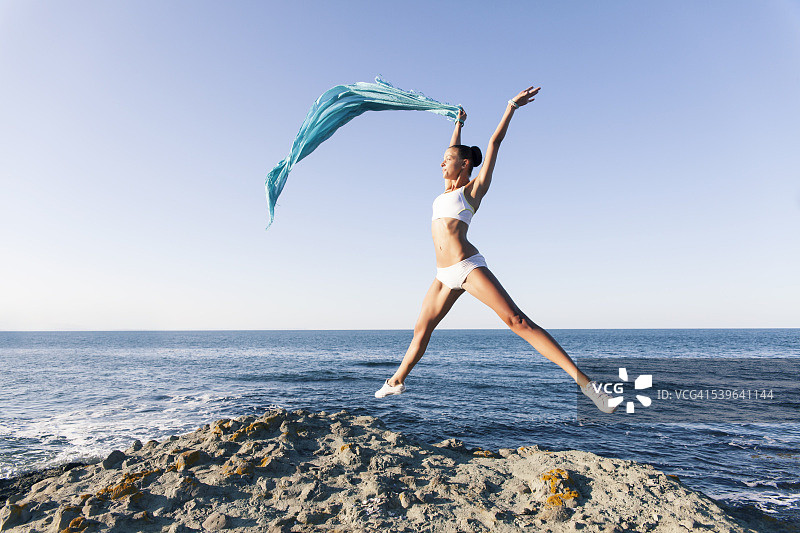 年轻女人跳跃并挥舞着蓝色面纱图片素材