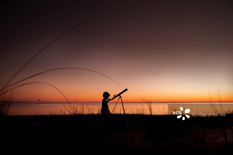 男孩用望远镜看星星的剪影图片素材