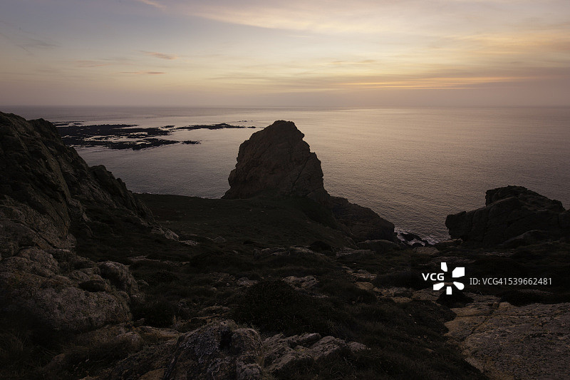 泽西岛：日落时分，海岸线上的岩石剪影图片素材