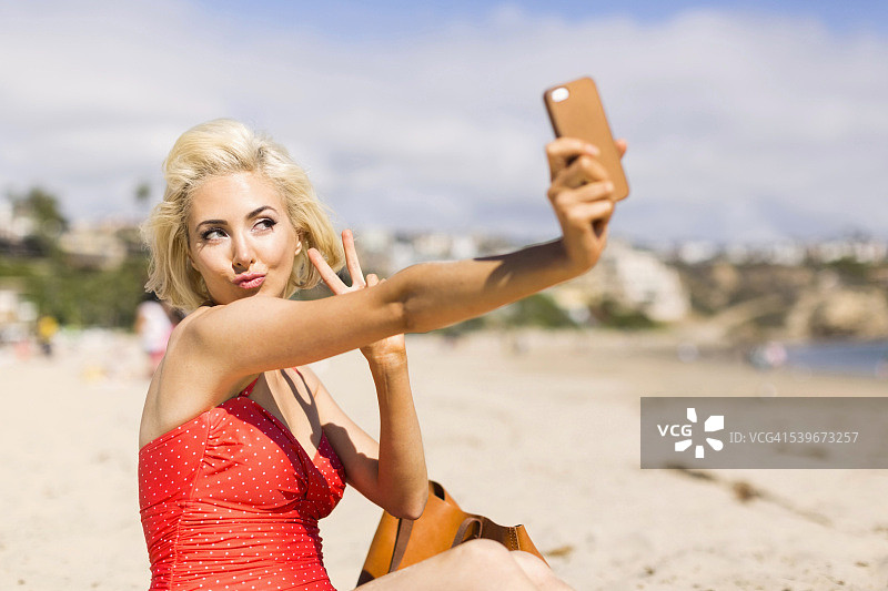 美国加利福尼亚州科斯塔梅萨，在海滩上自拍的金发女人图片素材