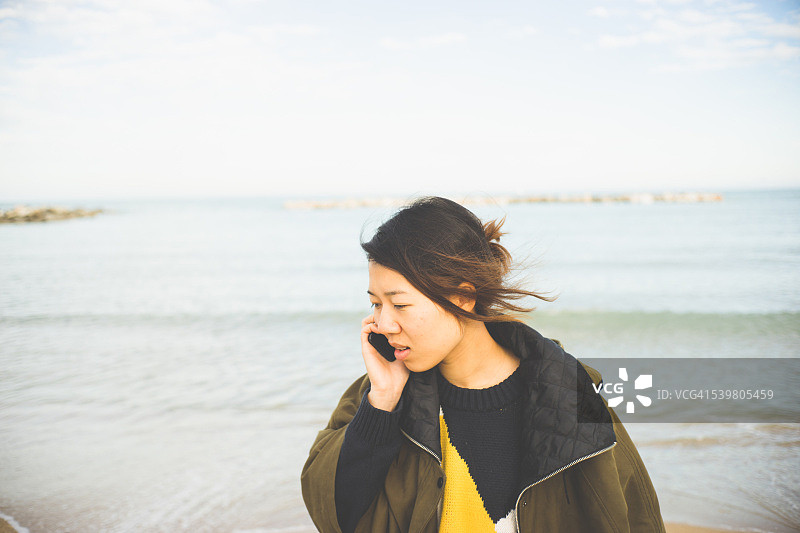 年轻女人在海滩上接电话图片素材