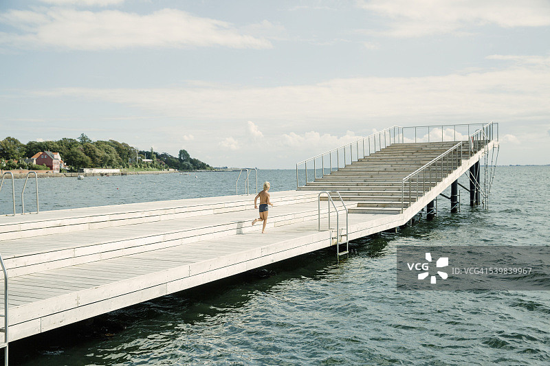 在港口浴场的木制码头上男孩图片素材