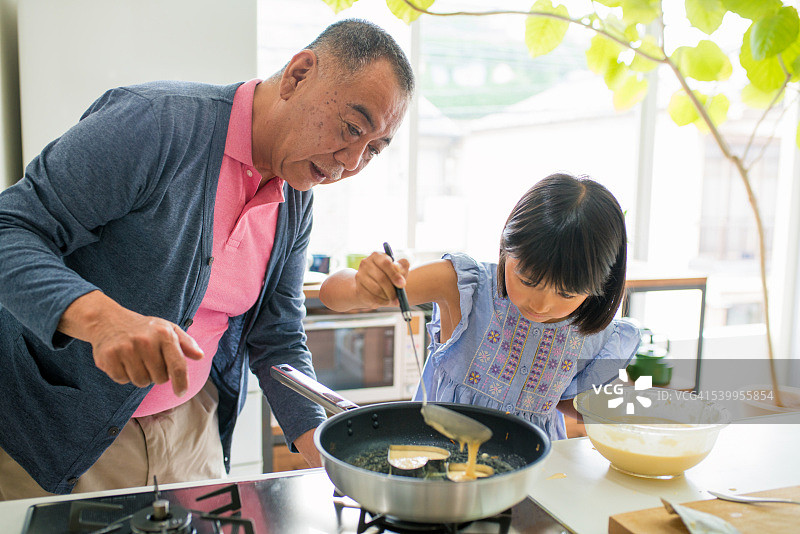 年轻女孩和她的祖父一起做饭图片素材