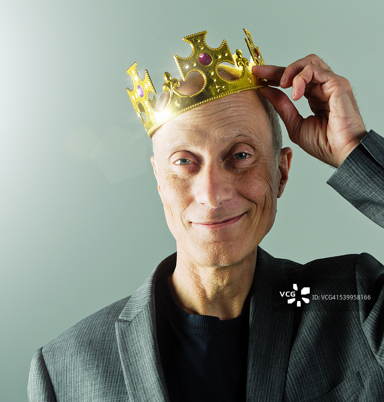 头戴皇冠、面带微笑的年长商人图片素材