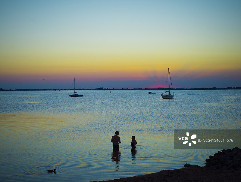 荷兰埃达姆海边日落，前景有鸭子和行人，如梦似幻图片素材