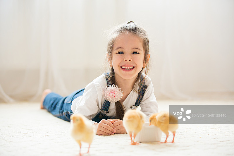 年轻漂亮的女孩在家里与新生小鸡玩耍，白色背景图片素材