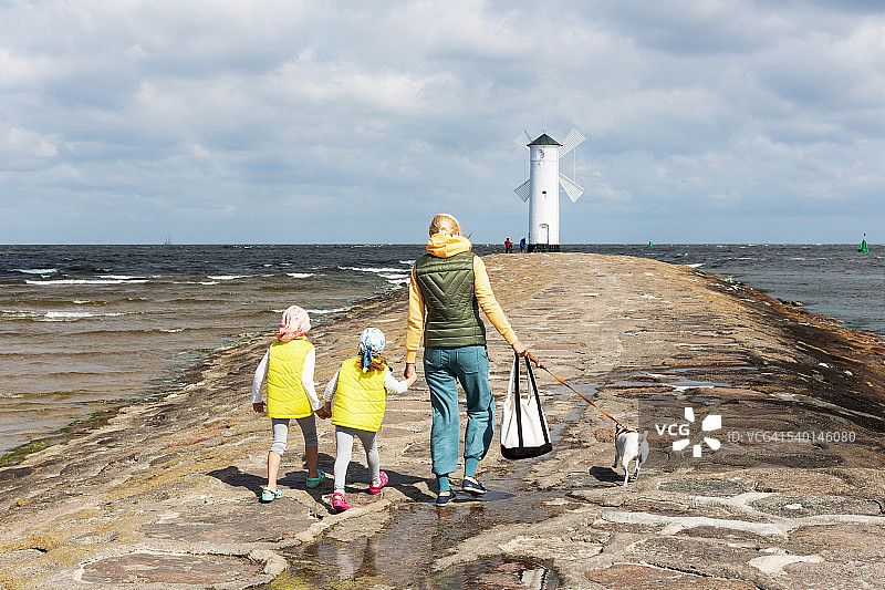 母亲带着两个孩子和她的狗在波兰希维诺乌伊希切的风车形状的穆赫伦贝克灯塔图片素材