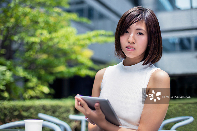 自信的日本女商人手持平板电脑的肖像图片素材