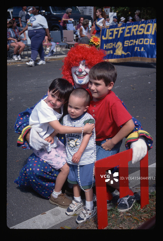 在游行中抱着孩子的小丑图片素材