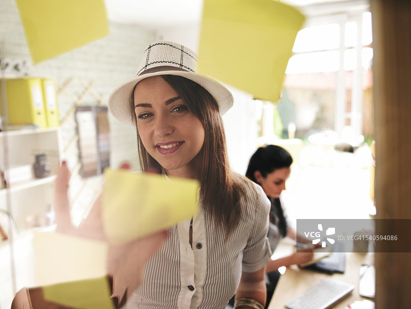 女人在玻璃板的便利贴上制作方案图片素材