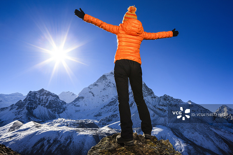 在喜马拉雅山脉中举起双臂欢呼的女人图片素材