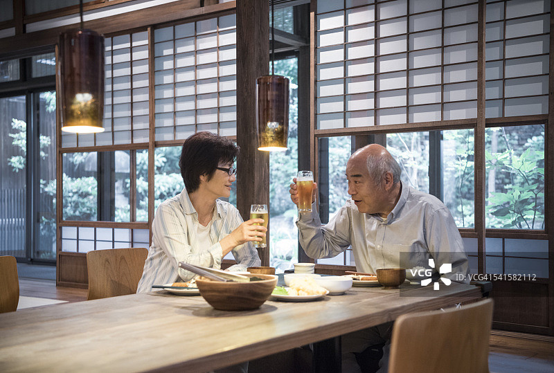 在晚餐时用啤酒杯祝酒的日本夫妇图片素材