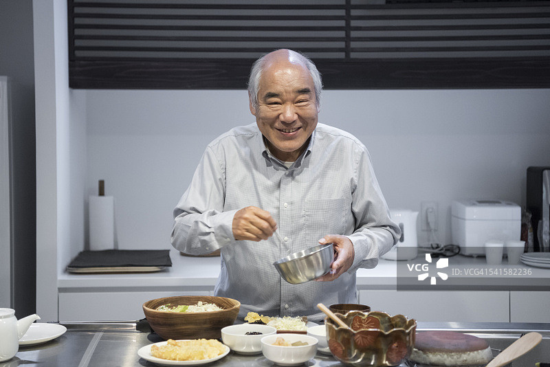 年长日本男人在厨房做饭，微笑图片素材
