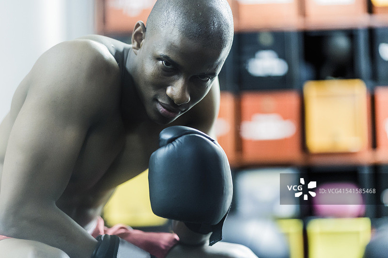 自信的拳击手坐在健身房里微笑图片素材