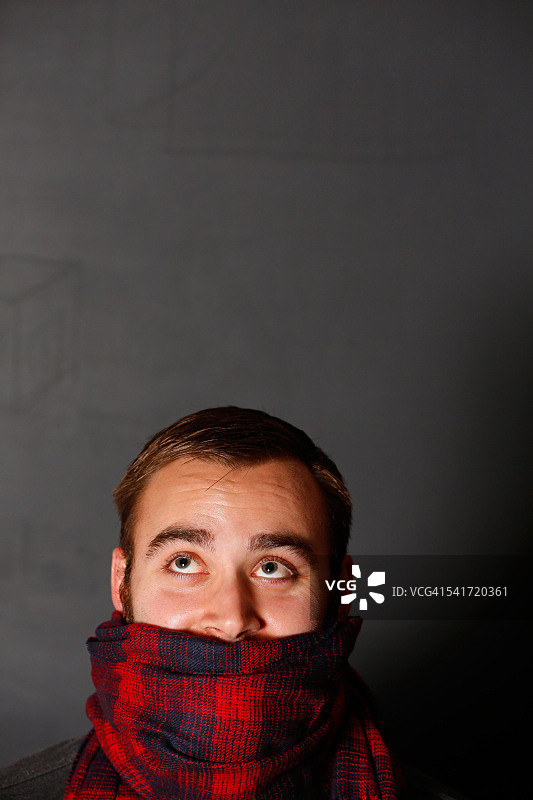 用格子围巾遮住嘴巴向上看的男人图片素材