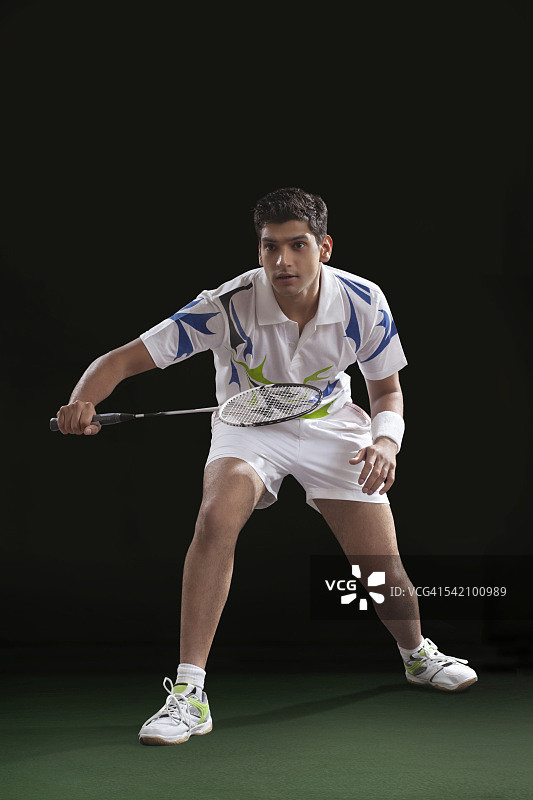 在黑色背景上打羽毛球的年轻男人图片素材