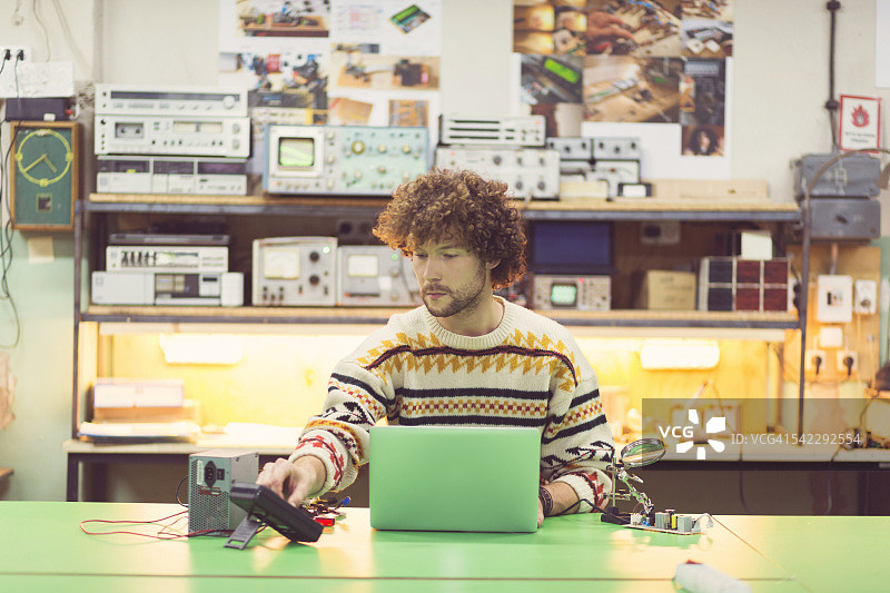 青年男子在电子车间使用笔记本电脑图片素材