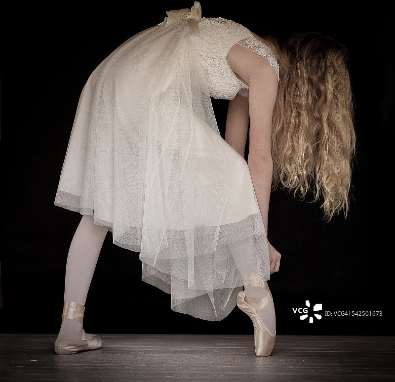 芭蕾舞者调整芭蕾舞鞋上的丝带图片素材