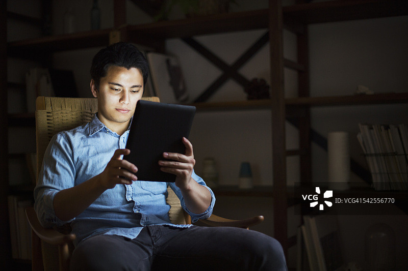 年轻男人在家中使用平板电脑图片素材