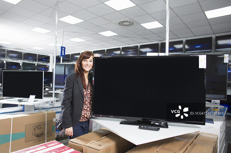 倚靠新电视机的年轻女人图片素材