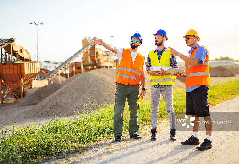 工程师在建筑工地戴着防护头盔，拿着蓝图图片素材