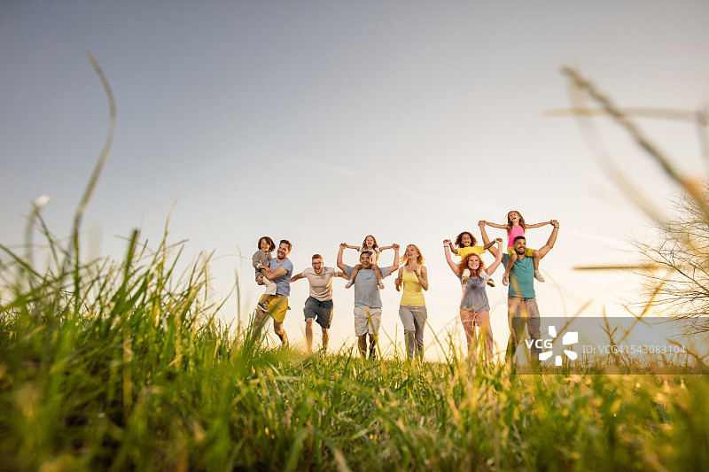 在日落时奔跑和欢笑的一大群快乐的人图片素材