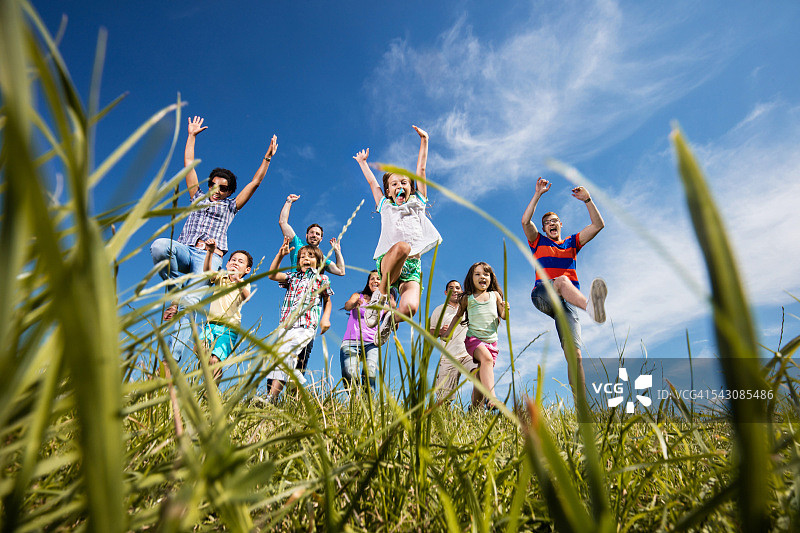 快乐的人们在草地上跳跃图片素材
