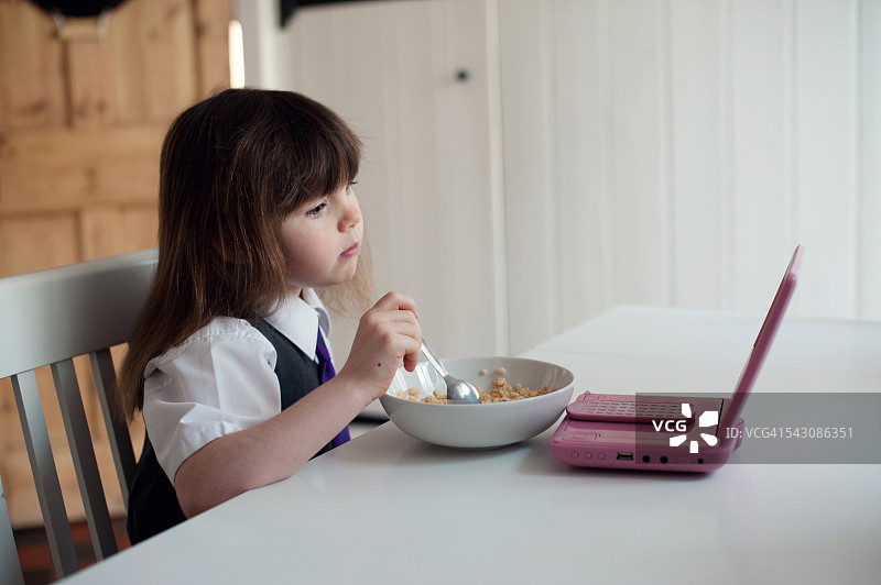 早餐时观看便携式DVD的女学生图片素材