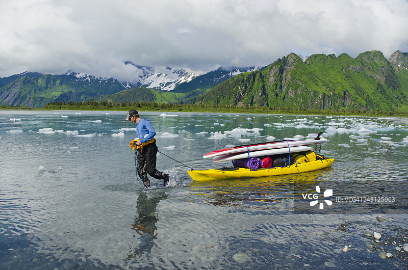 男子在皮划艇上搬运桨板和装备前往阿拉斯加熊湖和熊冰川图片素材