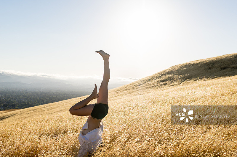 女子在阳光明媚的山丘上手倒立图片素材