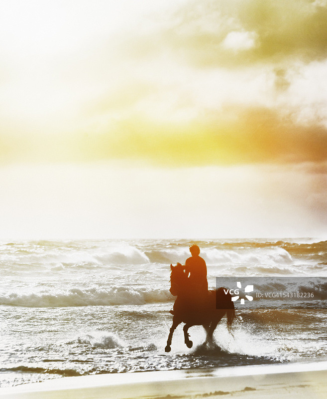 冬日午后在闪光浪花中奔驰的女骑手剪影图片素材