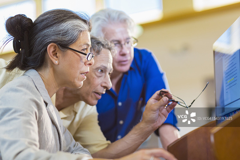 老师在图书馆帮助成年学生使用电脑图片素材