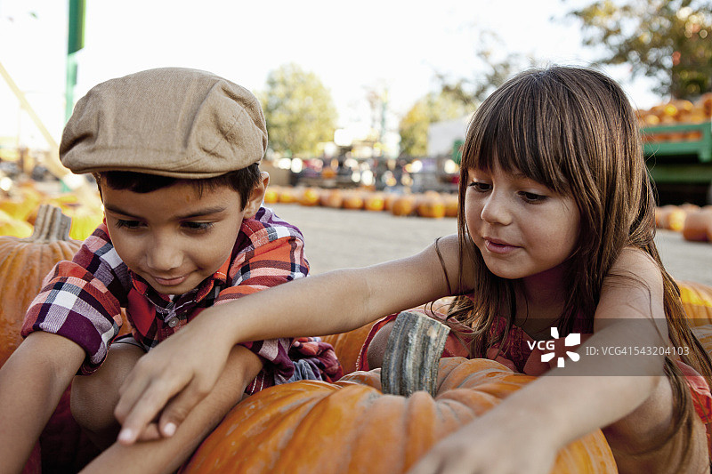 在农家庭院里，男孩和女孩伸手摘南瓜图片素材