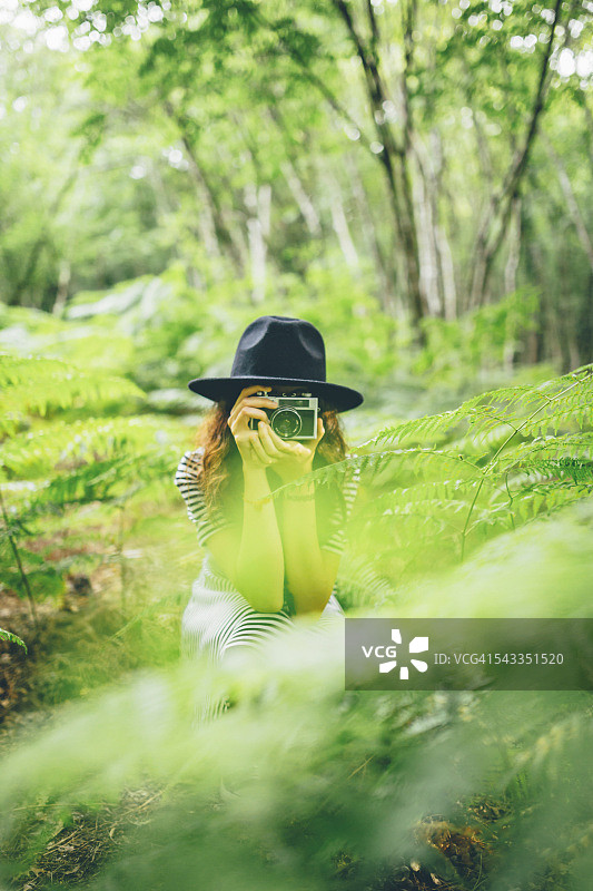 女孩用胶片相机在森林里拍照图片素材