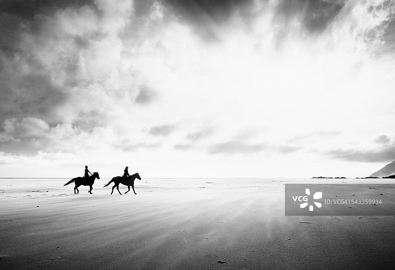 单色背景下穿越沙地的两名骑手图片素材