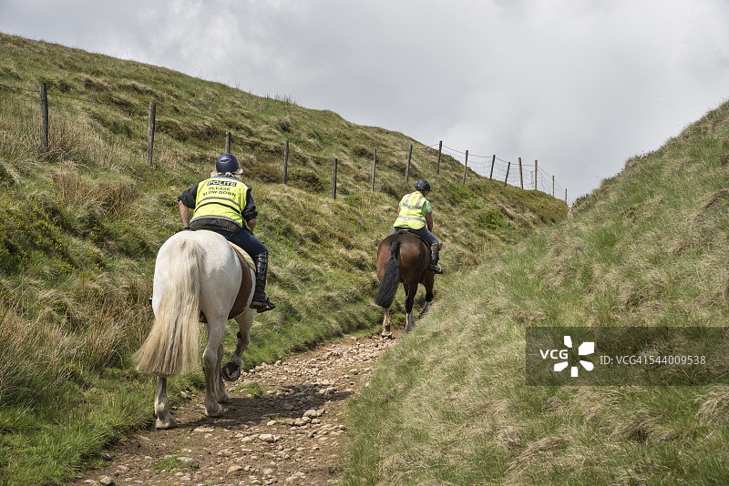 两名女子在岩石山坡小路上骑马图片素材