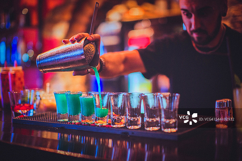 年轻的调酒师在酒吧调制鸡尾酒图片素材