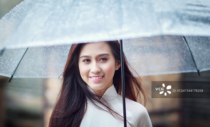 穿着奥黛的越南年轻女子在雨中撑伞图片素材