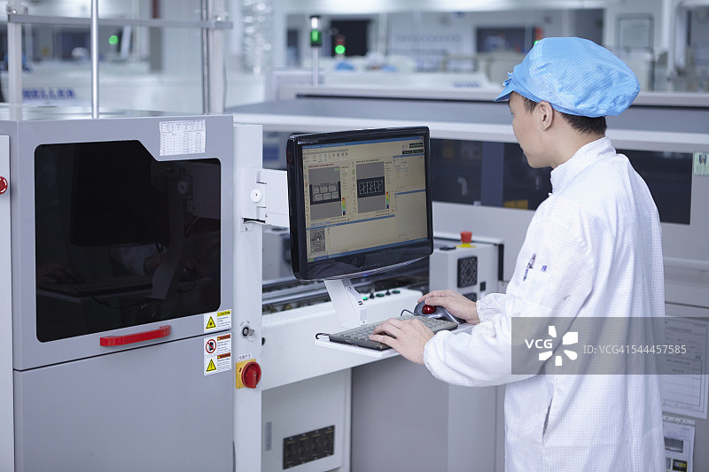 在工厂中使用计算机的工人，该工厂专门在柔性表面上创建功能电路图片素材