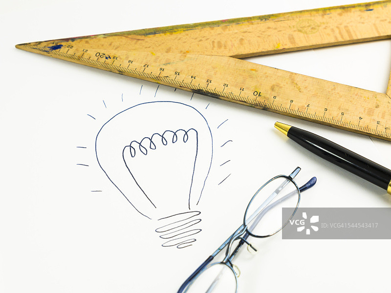 白纸上的灯泡、三角板、老花镜和圆珠笔图片素材