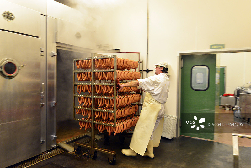 肉店里男人从熏房取出香肠图片素材