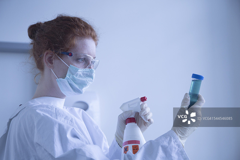 戴着口罩在生物化学实验室消毒测试的年轻女自然科学家图片素材