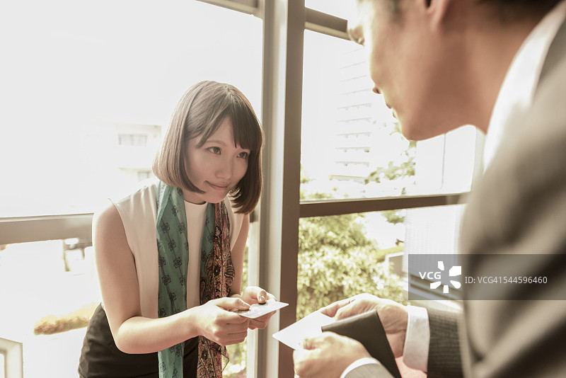 日本年轻女人向同事递交名片图片素材