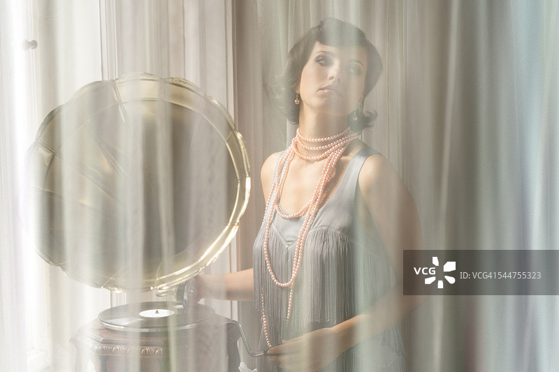 在窗帘后听留声机的女人图片素材