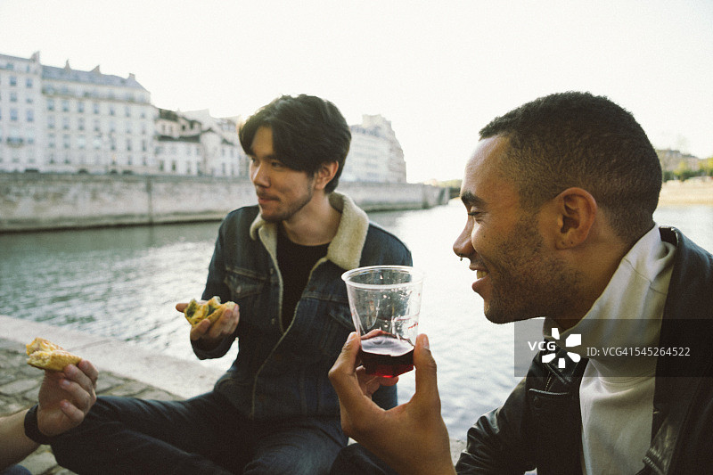 朋友们在日落时分的河边享用美食和葡萄酒图片素材