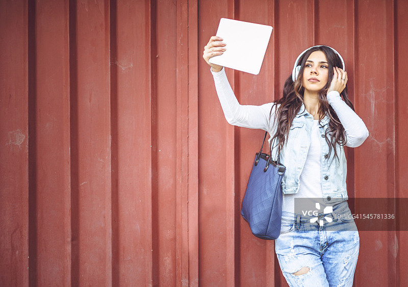 年轻微笑的学生戴着耳机自拍图片素材