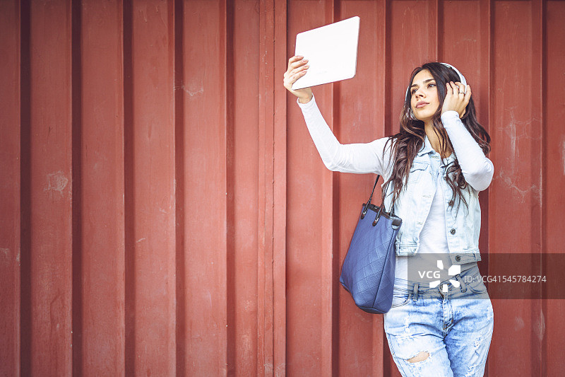 年轻微笑的学生戴着耳机自拍图片素材