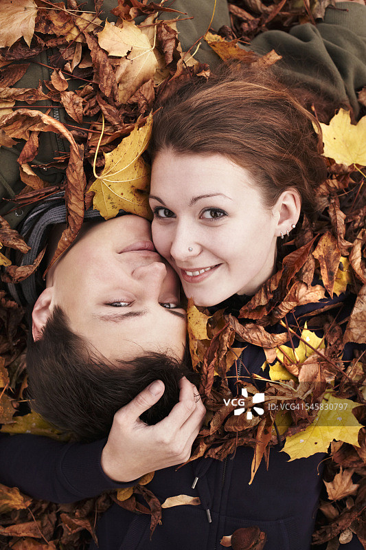 情侣躺在秋叶中图片素材