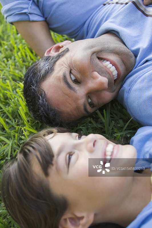 微笑的父女躺在草地上图片素材