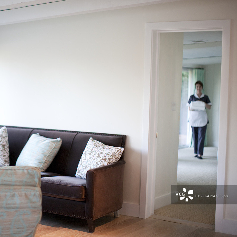 女服务员拿着毛巾走过酒店房间图片素材